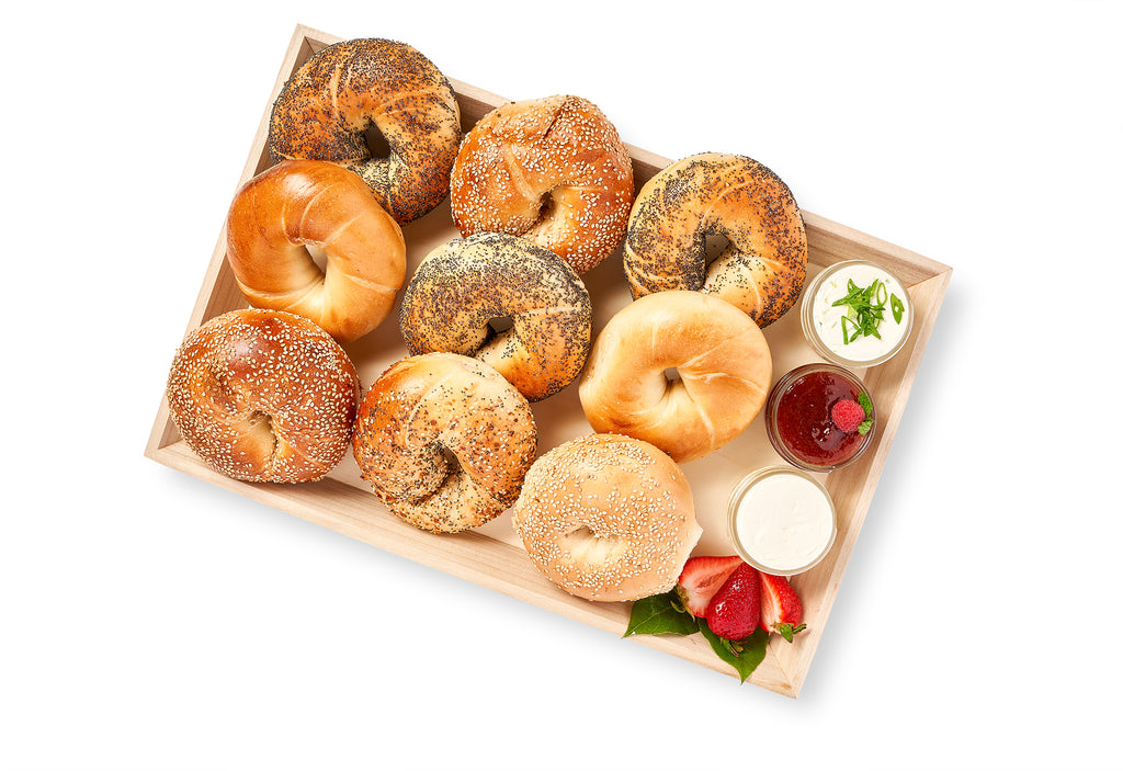 New York Bagel Platter topped with cream cheese and preserves on a wooden tray.