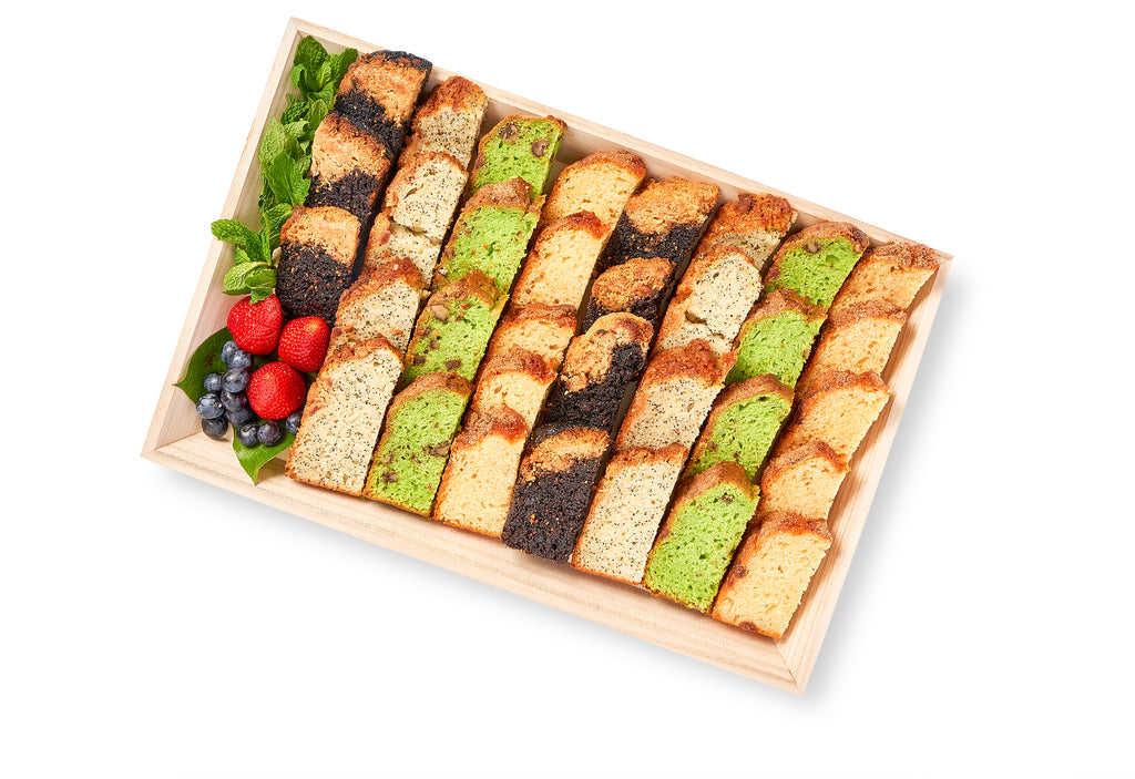 A wooden tray with a variety of Yogurt Loaves in different flavors, including pistachio.