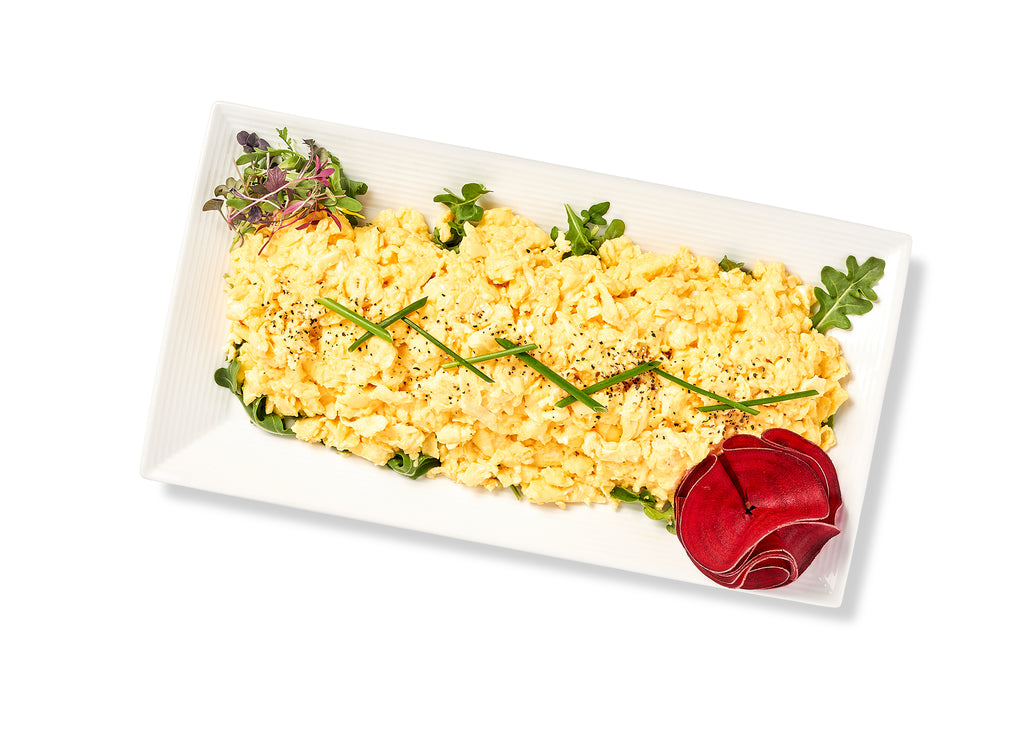 Scrambled Eggs on a white plate seasoned with salt and pepper.