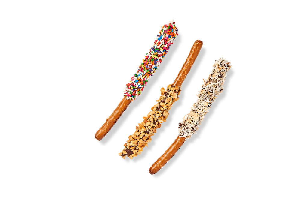 Three Chocolate Drizzled Pretzel Rods with sprinkles on them.