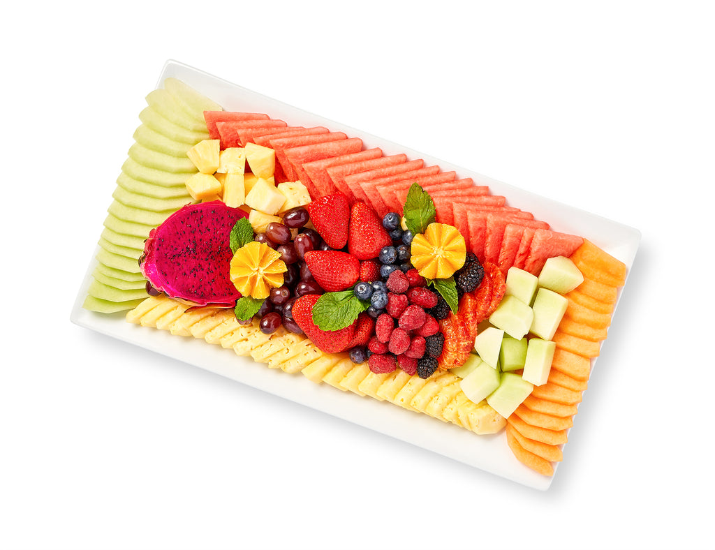 A white plate with a variety of Sliced Fresh Fruit, including tropical and seasonal fruit.