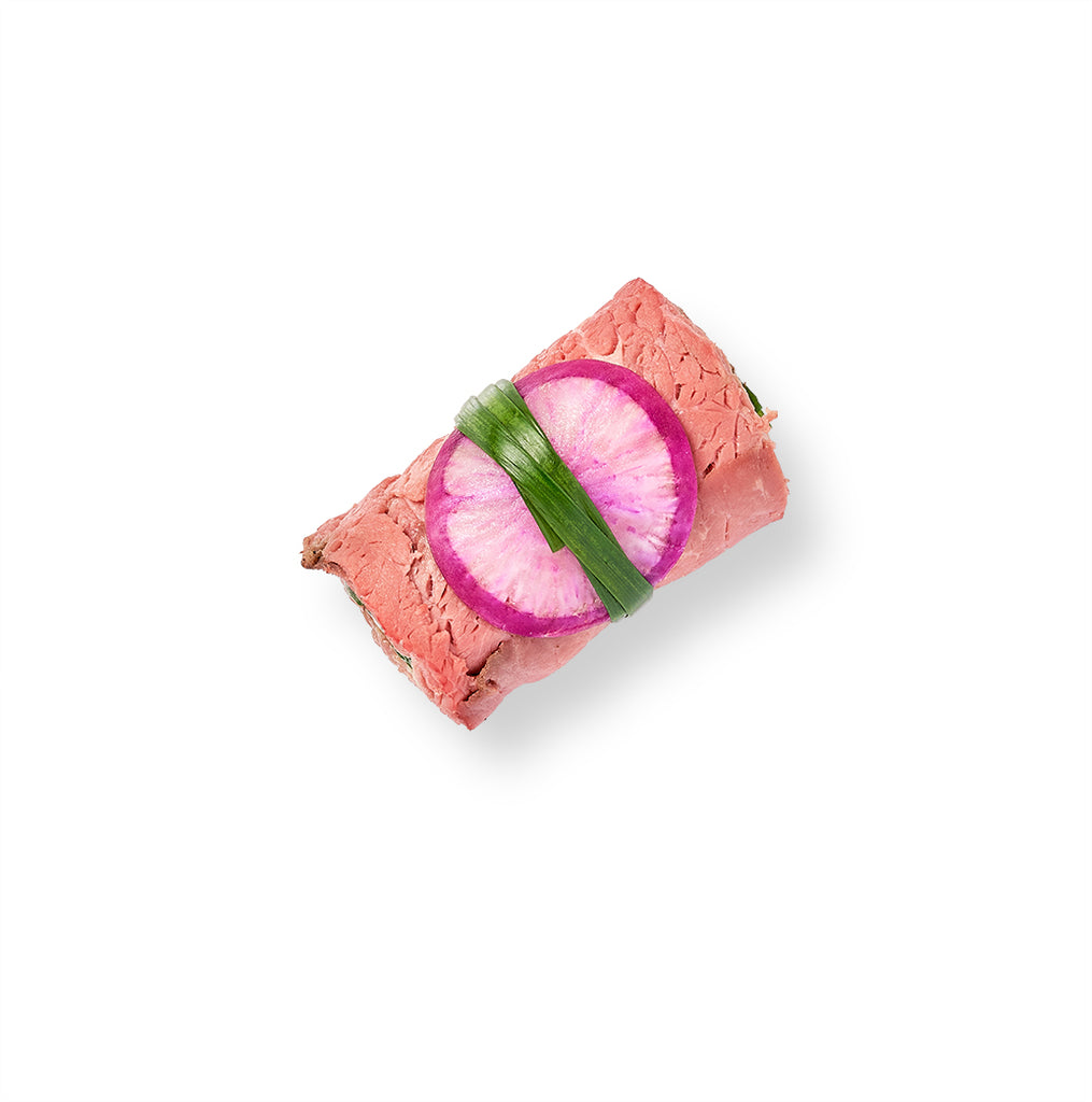 A sushi roll with a slice of Beef Roulade and radishes.