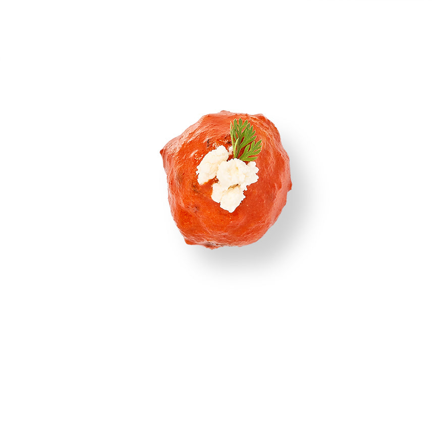 An image of a Buffalo Chicken Meatball on a white background with caramelized onion.