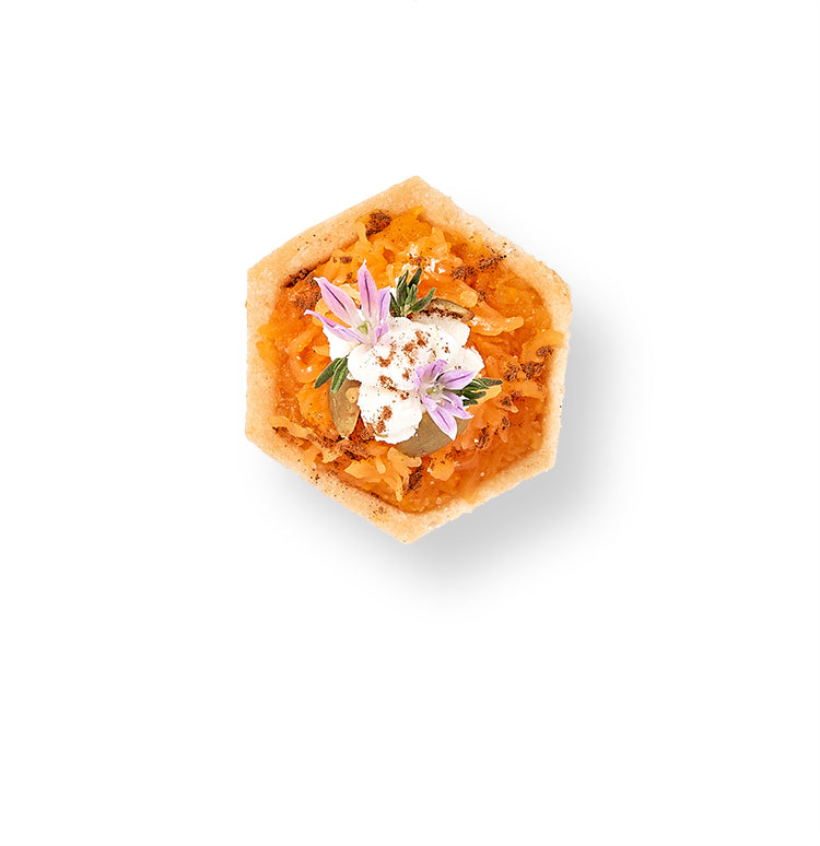 A small dish with diced carrots and seasonal flowers in a Butternut Squash Tartlet shell.