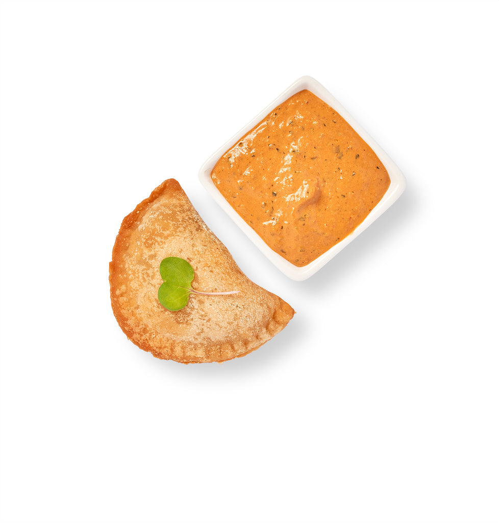 Accompanied by Mini Chicken Empanadas, a pie with sauce and a leaf on a white background.
