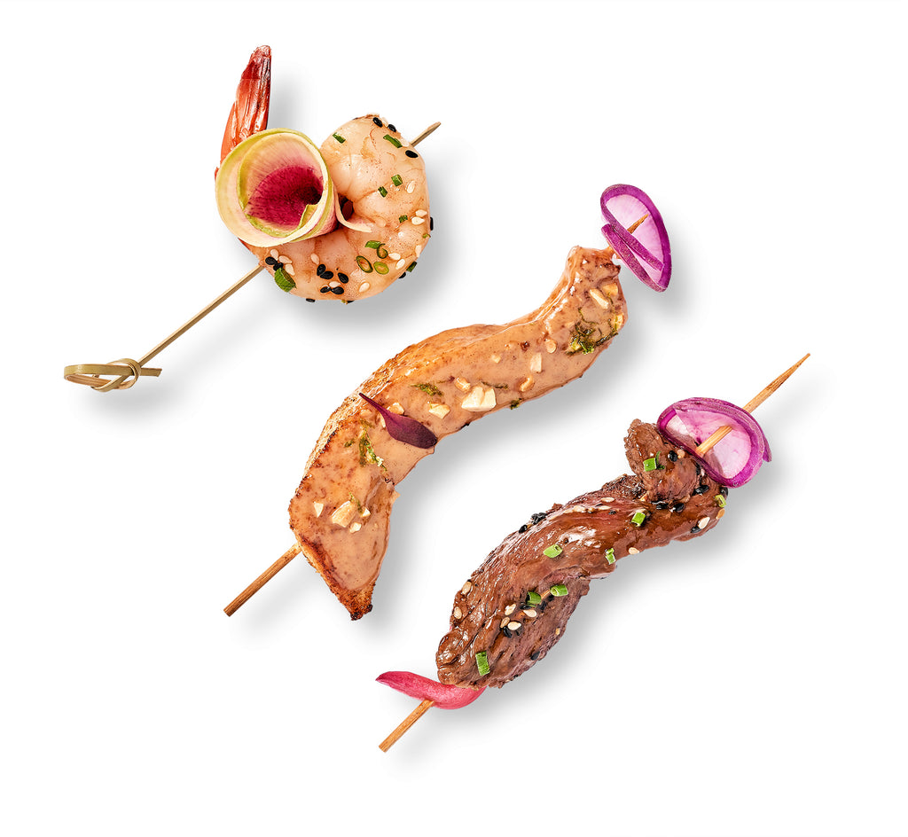 Three Hors D'Oeuvres in a Box on skewers on a white background.
