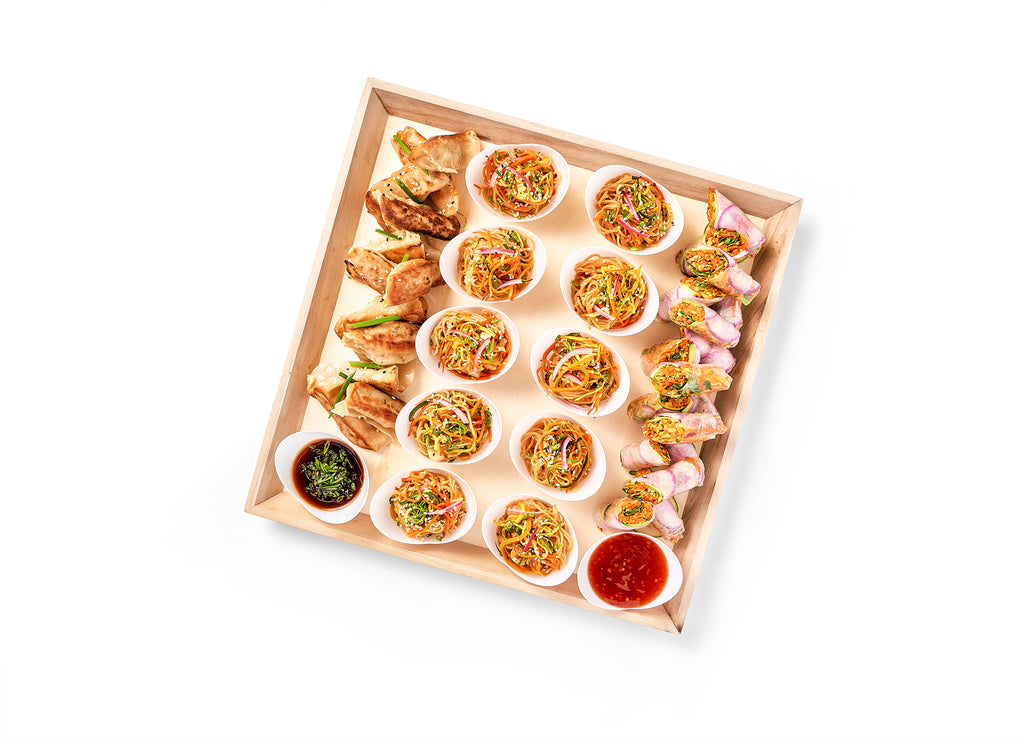 A wooden tray with a variety of food on it, including a Chinese Party Platter with Hoisin Spring Rolls and Mini Sesame Noodles.