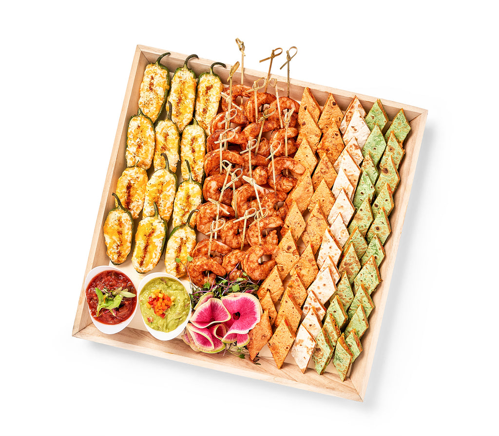 A wooden tray with a variety of food including Southwest Party Platter.