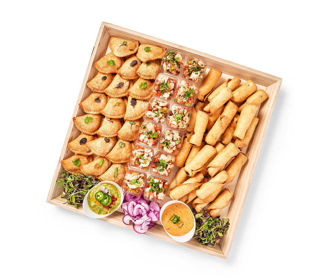A wooden tray with a variety of Mexican Party Platter, Chicken Taquitos, and dips.