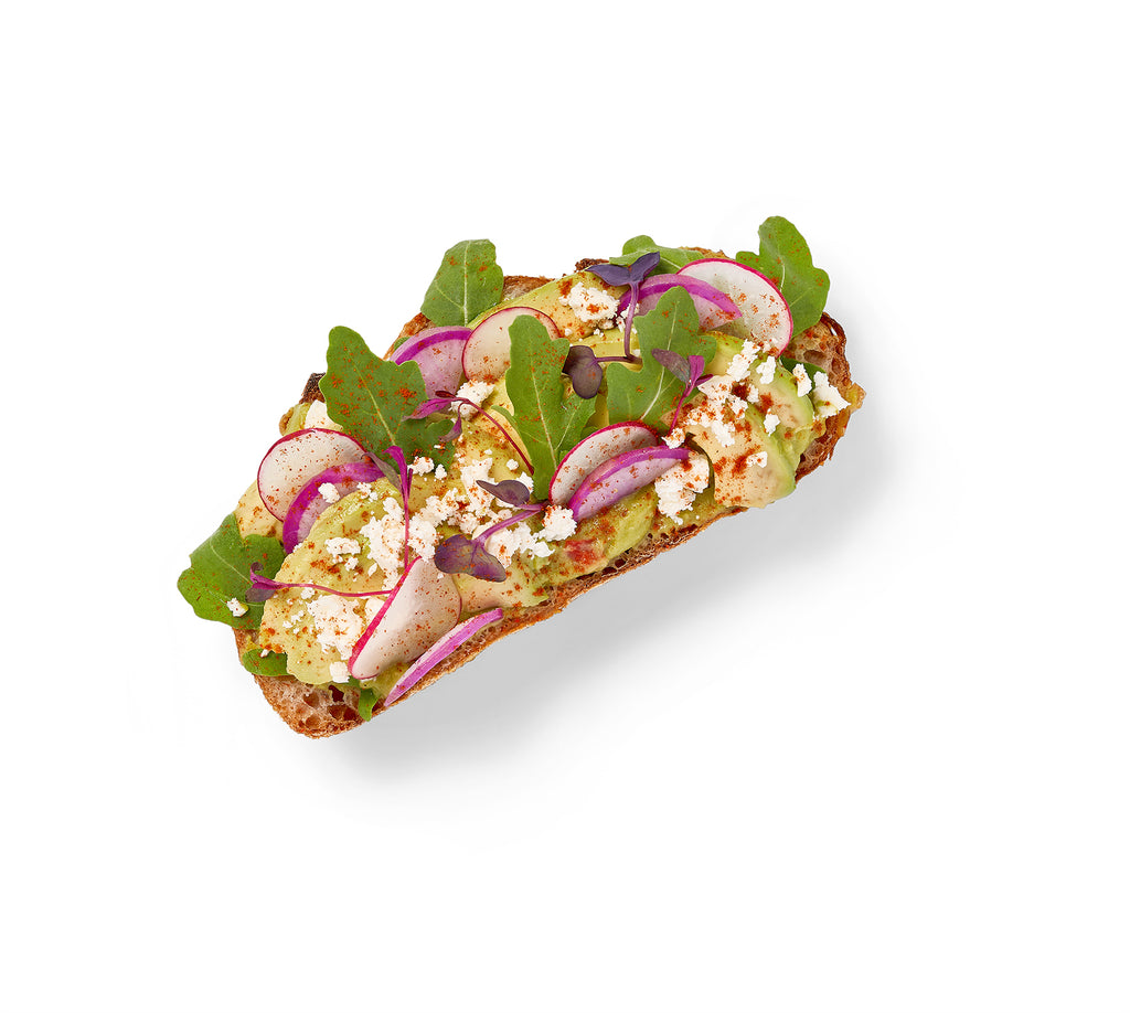 A Breakfast Sandwich in a Box with radishes and greens on a white background.