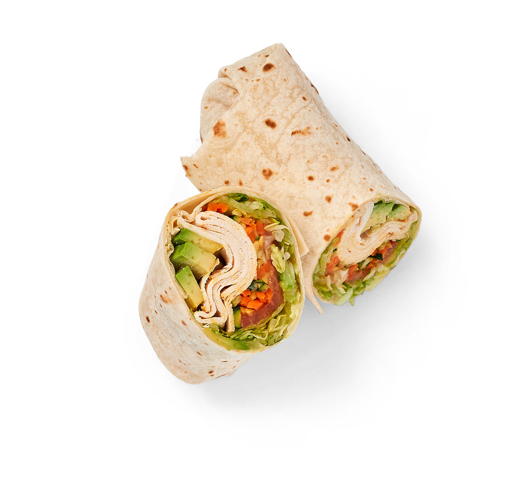 White wrap cut in half with Fresh Roasted Turkey, Bacon, Vegetables and avocado