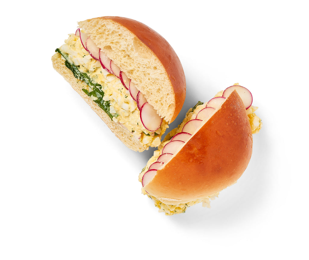 Two Egg Salad Sandwiches with eggs and radishes on a white background, creating a classic combination.