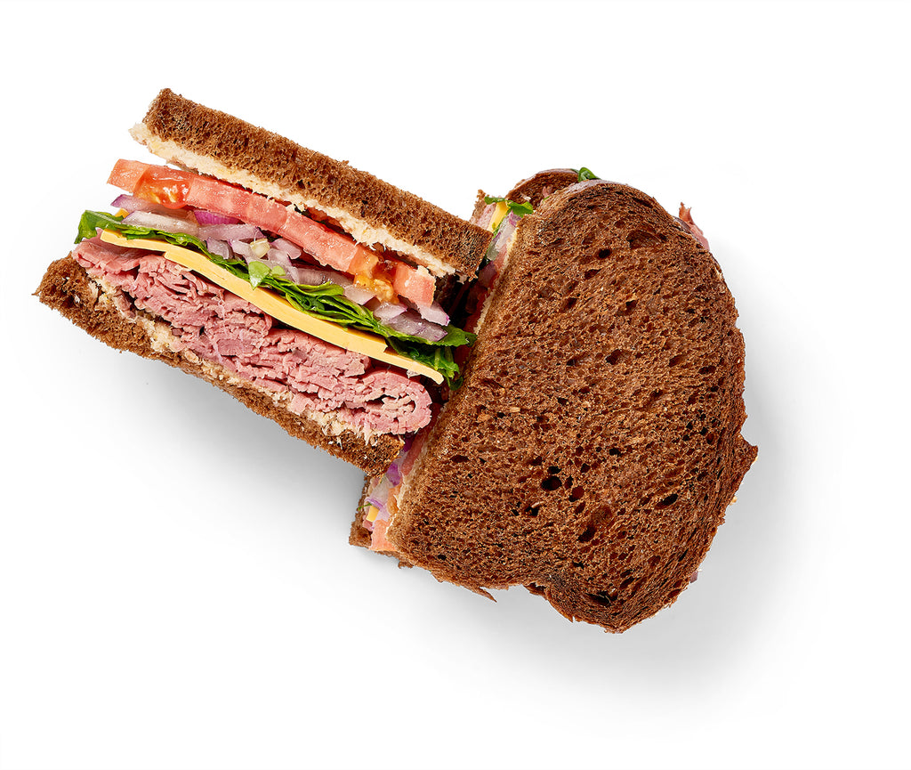 A Rare Roast Beef Sandwich cut in half on a white background.