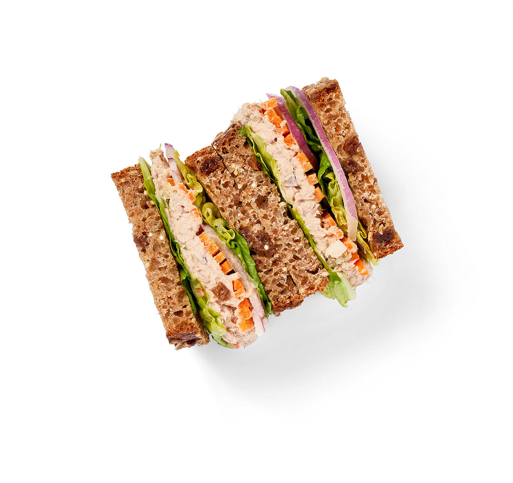 A Tuna Salad Sandwich with lettuce and carrots on a white background.