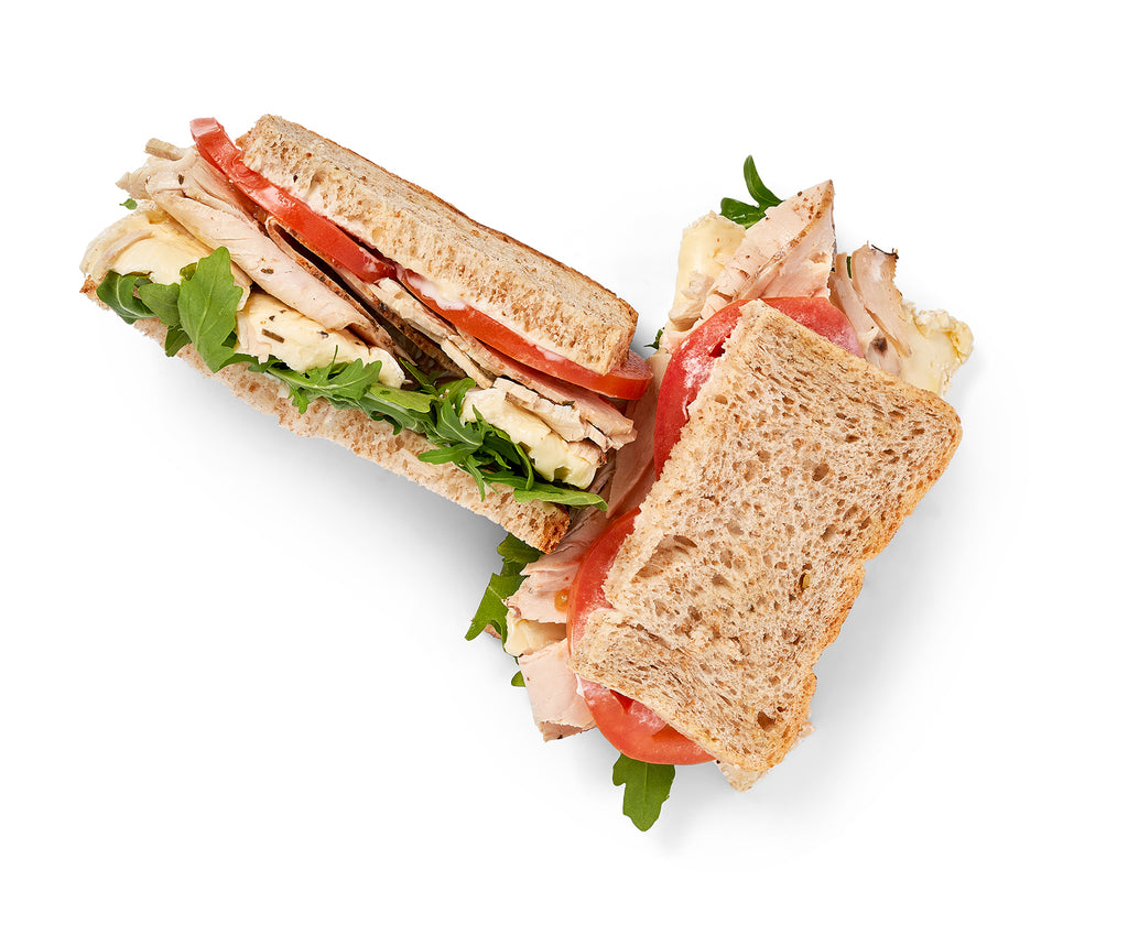 The Fresh Roasted Turkey Sandwich is cut in half on a white background.