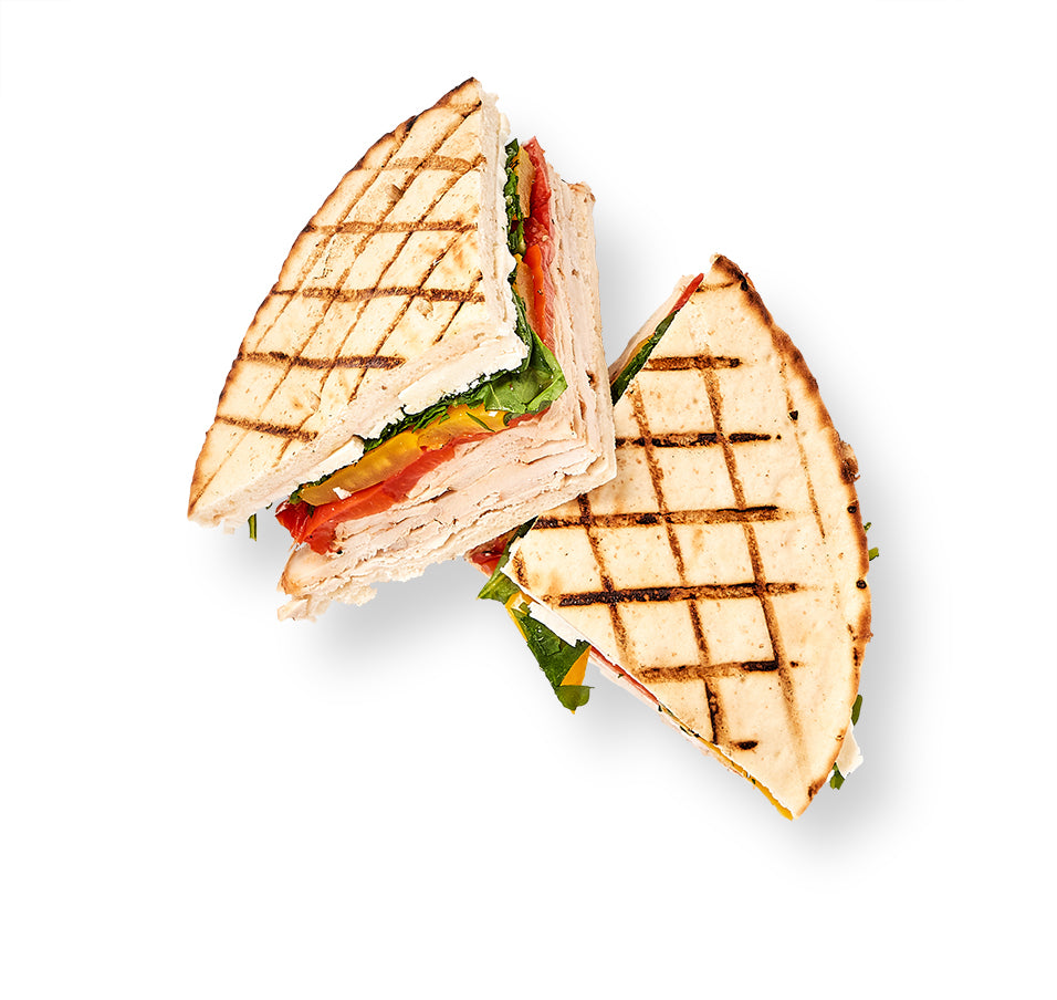 A Reuben Panini is cut in half on a white background.