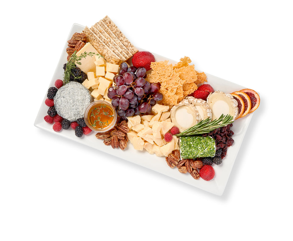 A white platter with Artisanal Cheese and Crackers, dried fruits, and nuts.