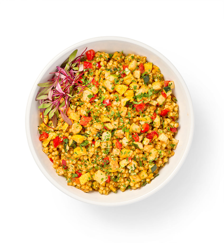 A bowl of Israeli Couscous Salad on a white background.