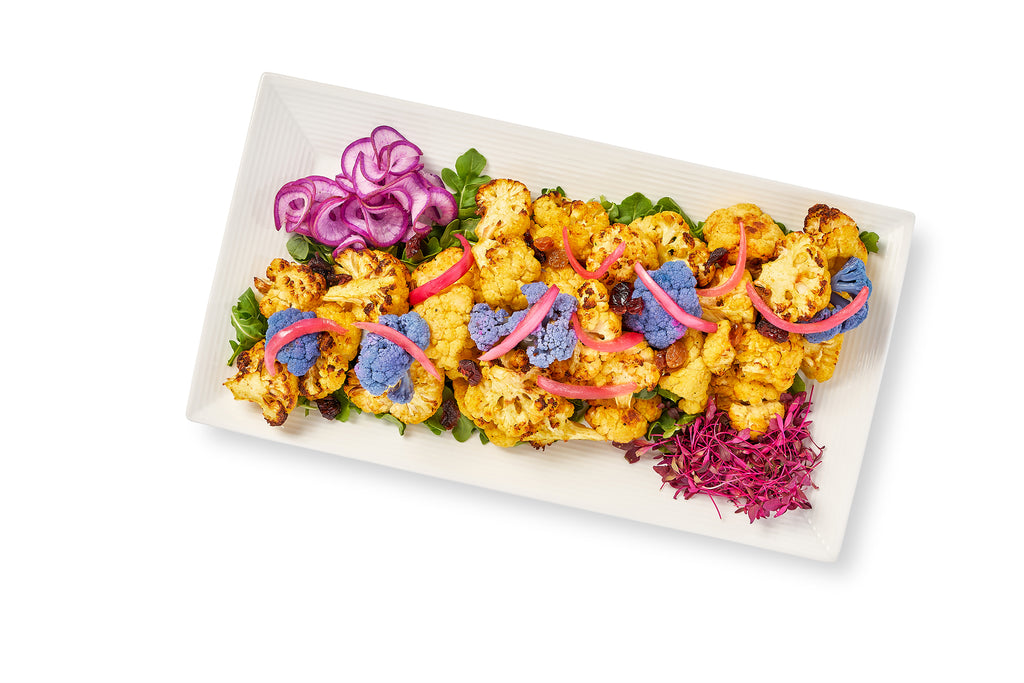 A plate of Middle Eastern Spiced Cauliflower topped with caramelized shallots on a white plate.