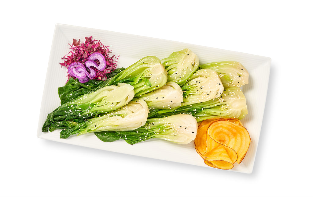 Sauteed Baby Bok Choy on a white plate with vegetables on it.